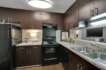 A modern kitchen with dark brown cabinets and black appliances.
